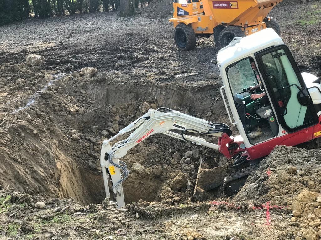 Bagger in einer grossen Baugrube, Dumper im Hintergrund
