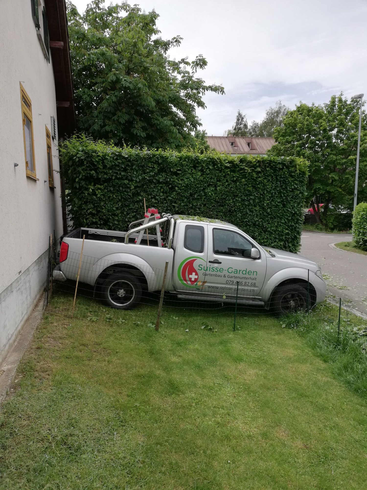 Firmenfahrzeug von Suisse-Garden vor einer geschnittenen Hecke