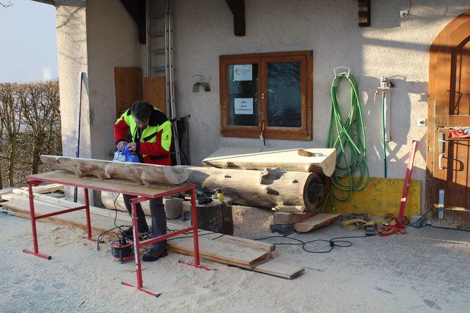 Holzbearbeitung auf Böcken vor dem Haus