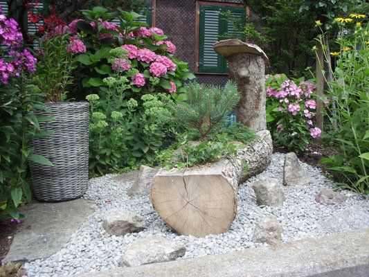 Baumstamm als Pflanzgefäss zwischen Hortensien